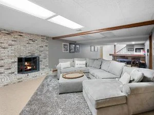Modern living room with brick fireplace, gray sectional sofa, and recessed lighting