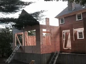 Two-story home addition with new framing, deck, and stairs under construction