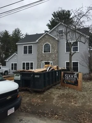 Two-story home addition with new siding, windows, and dumpster on-site during construction