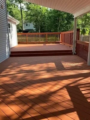 Composite deck with diagonal board pattern and covered patio overhead, wood-tone railings