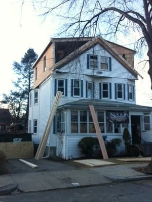 Three-story home with new vinyl siding, roof framing, and exterior renovation in progress