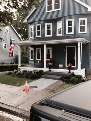 Gray vinyl sided home with white front porch, composite decking, and white railings