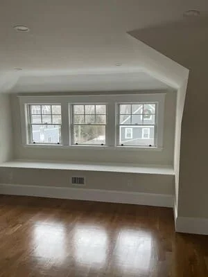 White drywall window seat with three double-hung windows, recessed lighting, and hardwood flooring