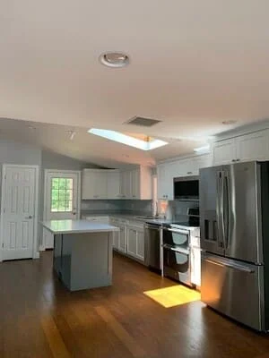 Modern kitchen with gray cabinets, stainless steel appliances, center island, and hardwood floors