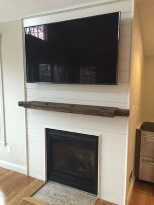 White shiplap fireplace surround with floating wood shelf and mounted TV above