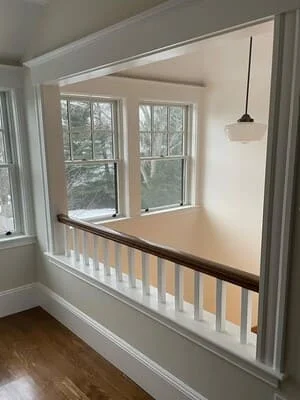 Custom window seat with white spindle railing and dark wood cap rail beneath dual windows