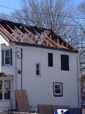Fire-damaged home with exposed framing and charred roof structure during restoration work