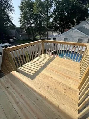 Newly built pressure-treated wood deck with railing and decking boards